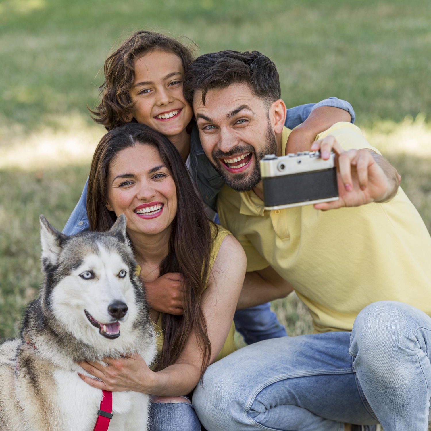 father-taking-selfie-of-the-family-and-dog-while-out-in-the-park